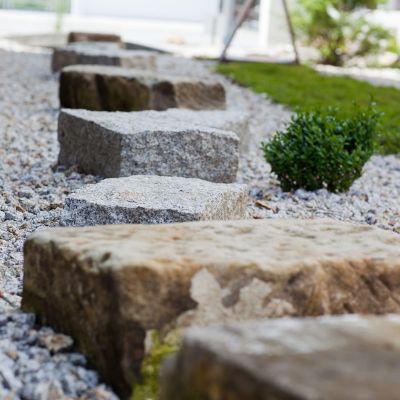 Natursteine als Gehweg auf Kiesbett im Garten