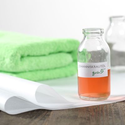 Flasche mit Johanniskrautöl neben grünem Handtuch